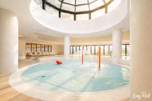 a large swimming pool in a building with a domed ceiling at Prestige 204 - tuż przy plaży - Easy-Rent Apartments in Pobierowo