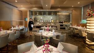 a woman walking through a dining room with tables and chairs at Royal Orchid Central Vadodara in Vadodara