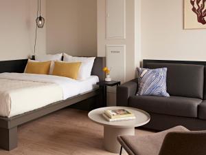 a bedroom with a bed and a couch and a table at Numa Cologne Ehrenfeld in Cologne