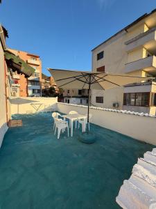 a patio with a table and an umbrella on a building at Guest house Luli Mucaj in Çorovodë