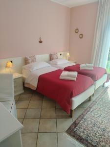 a bedroom with two beds with red and white sheets at Villa Campo dei Fiori in Casciago