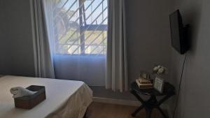 a bedroom with a bed and a window and a table at Terrys place in Malmesbury