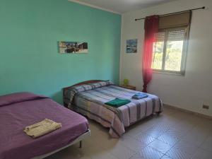 a bedroom with two beds and a window at Villa Giù, indipendent villa near airport and sea in Cinisi