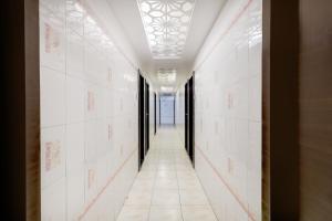 a hallway with white tile walls and a ceiling at Collection O Chidambaram Stadium Formerly Hotel Admire Suit in Chennai