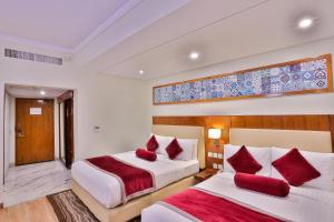 two beds in a hotel room with red pillows at Avari Xpress Multan in Multan +23 photos