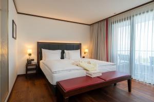 a bedroom with a large white bed with a red bench at Bad Horn - Hotel & Spa in Horn