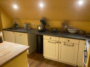 a kitchen with white cabinets and a black counter top at Charmantes und geräumiges Loft im DG eines Fachwerkhauses in Dortmund +5 photos