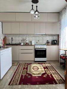 a kitchen with white cabinets and a rug on the floor at Central Guest House Karakol in Karakol