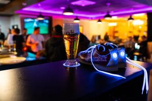a glass of beer sitting on a bar with a shoe at Hotel Kristály Konferencia & Wellness in Ajka