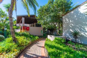 a brick walkway in front of a house with palm trees at Zenith Place, Port St Francis in Cape St Francis