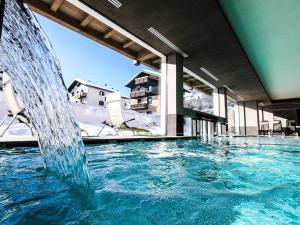 a large swimming pool with a water fountain at Francesin Active Hotel in Livigno