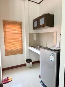 a small kitchen with a sink and a refrigerator at Laydee Resort in Chumphon