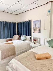 two beds in a room with blue curtains at Laydee Resort in Chumphon