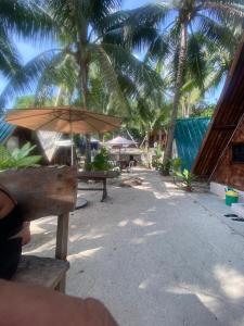 a table with an umbrella on a beach with palm trees at Sea Breeze Camp in Siquijor
