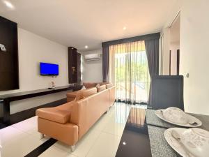 a living room with a couch and a television at Westkey Kamala Hotel in Kamala Beach