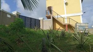 a yellow house with a staircase on the side of it at Executive Apartment in Cape Coast