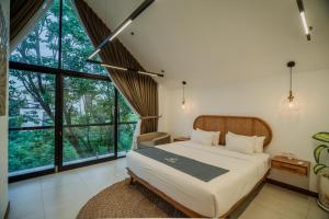 a bedroom with a large bed and large windows at Premier Umalas Villas in Seminyak