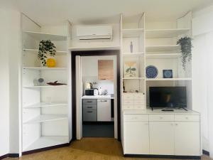 a white kitchen with white shelves and a television at Onda blu in Marina Julia +6 photos