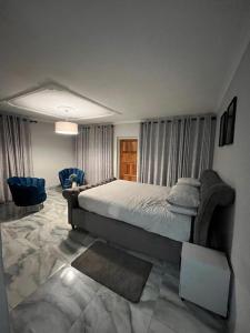 a bedroom with a large bed and blue chairs at The Savannah Escape in Norton