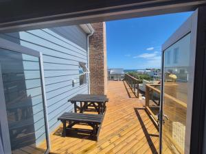 a wooden deck with a picnic table on a balcony at Net Genoeg in De Kelders