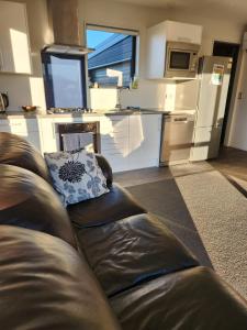 a living room with a leather couch and a kitchen at Twizel getaway in Twizel