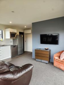 a living room with a leather couch and a kitchen at Twizel getaway in Twizel