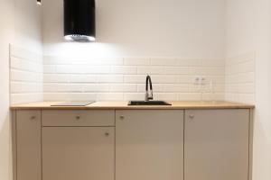 a kitchen with white cabinets and a sink at Starowiejska Residence 1860 in Miejsce Piastowe +7 photos