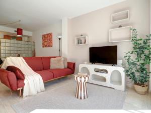 ein Wohnzimmer mit einem roten Sofa und einem Fernseher in der Unterkunft Bonaire Apartment by Hello Homes Sitges in Sitges
