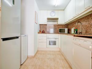 Eine Küche mit weißen Schränken und weißen Geräten in der Unterkunft Bonaire Apartment by Hello Homes Sitges in Sitges + 11 Fotos