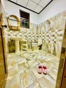 a bathroom with a toilet and a pair of pink slippers at Kings Garden House in Weligama