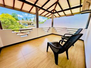 a black chair sitting in a room with a balcony at Kings Garden House in Weligama