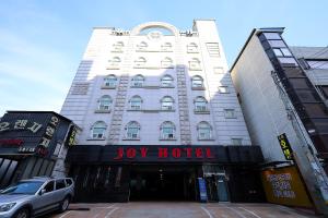 a large white building with a joy hotel at Ingye Joy Hotel in Suwon