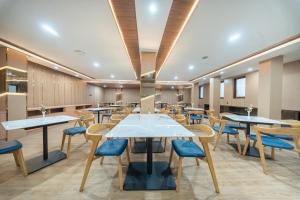 a dining room with tables and blue chairs at Horison IJ Kudus in Kudus