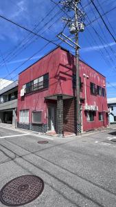 a red building on the corner of a street at ゲストハウス のまー in Komagane
