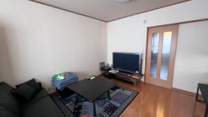 a living room with a couch and a television at ゲストハウス のまー in Komagane