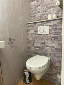 a bathroom with a toilet and a brick wall at Outdoors Holten - Forest Cabin in Holten
