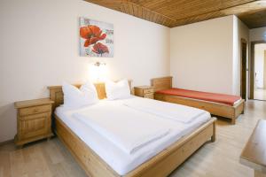 a bedroom with a large white bed and a bench at Pension Seehof in Holzöster +30 photos