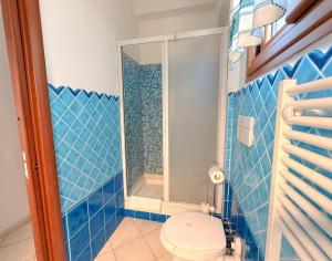 a blue tiled bathroom with a toilet and a shower at LE TERRAZZE Apartment - spacious and charming apartment near the sea and beach, close to the train station with hourly trains to Rome - Lido delle Sirene, Anzio in Anzio +25 photos
