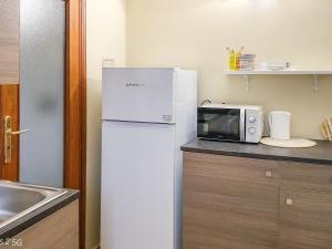 a kitchen with a white refrigerator and a microwave at Nel Centro Storico in Luserna San Giovanni +34 photos