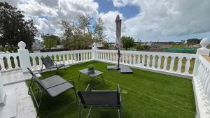a white fence with chairs and a table on a lawn at Finca La Arboleda in Chipiona