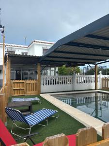 a patio with a pool and two chairs and a table at Finca La Arboleda in Chipiona