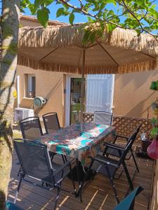 a table with chairs and an umbrella on a deck at Le Petit Marais in Échiré
