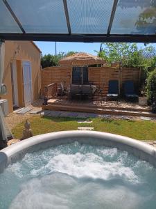 a hot tub in a yard with an umbrella at Le Petit Marais in Échiré