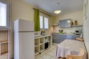 a kitchen with a white refrigerator and a table at La Colline des Pins in Aniane
