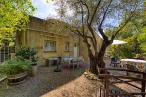 a patio with a table and a tree in front of a building at La Colline des Pins in Aniane