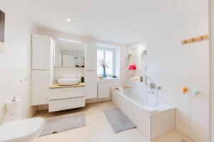 a white bathroom with a tub and a toilet and a sink at Hotel Hochfirst in Lenzkirch +79 photos