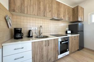 a kitchen with wooden cabinets and a sink and a refrigerator at Ferienwohnung Penthouse Sunce in Bar +1 photo
