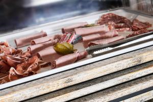 a display case with hot dogs and other meats at Logis Hôtel Le Relais in Biscarrosse