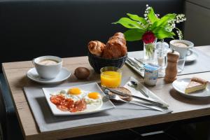 a breakfast table with eggs and croissants and coffee at Logis Hôtel Le Relais in Biscarrosse +42 photos