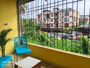 a blue chair sitting next to a window with a view at Mon Aashray Stay in Guwahati
